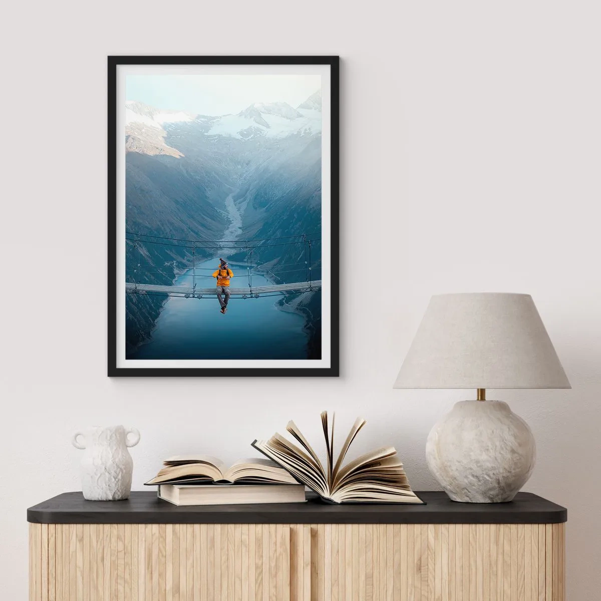 Poster in black frame - A person in a yellow jacket sitting on a suspension bridge over a valley - 50x70cm - Suspended in Delight - Modern wall decoration for the living room and bedroom ARTTOR